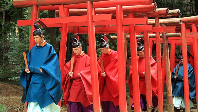 sacerdotes sintoístas pasando a través de un sendero de torii