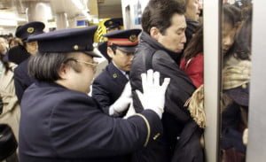 Guardias de la estación empujando a pasajeros en un metro de Tokyo
